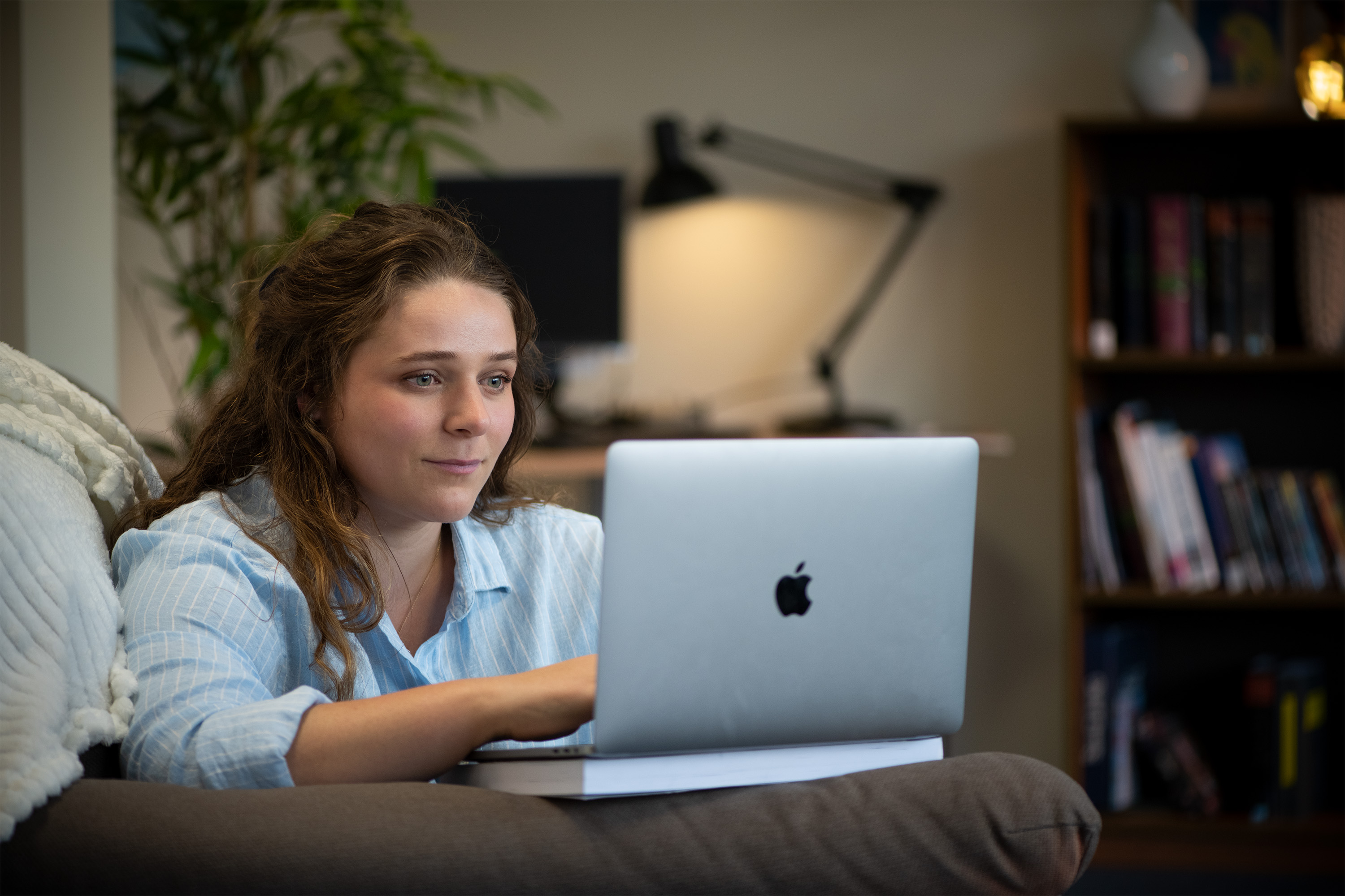 Student Victoria studying on her laptop whilst sitting in her living room on the sofa. 