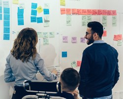 Group meeting mind-mapping thoughts on post-it notes stuck to wall 