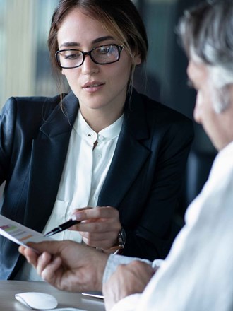 Older male reviewing documents with woman in smart clothing