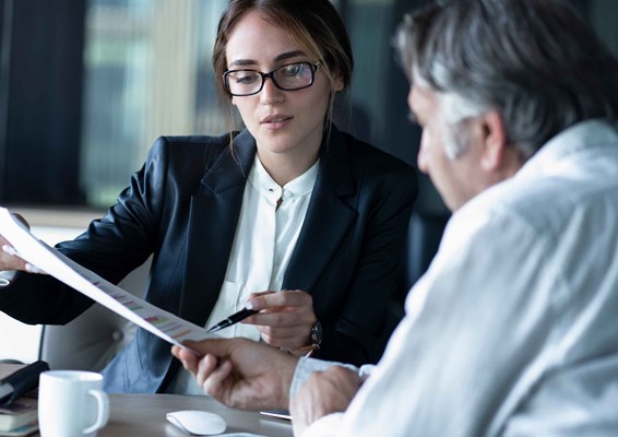 Older male reviewing documents with woman in smart clothing