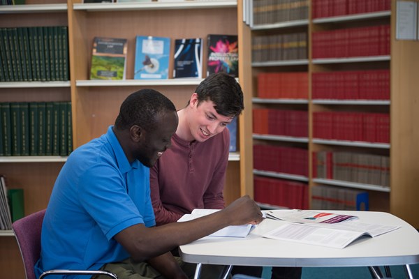 Two students studying together in a library