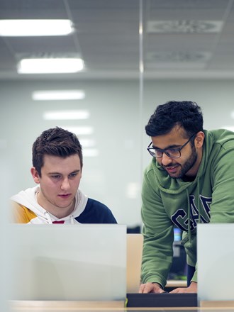 Two students studying and looking at a laptop together