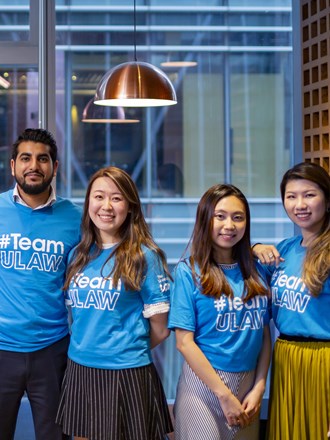 A group of ULaw students smiling and wearing #TeamULaw t-shirts