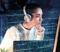 Woman wearing headphones and looking at data on a computer