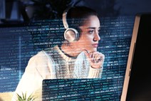 Woman wearing headphones and looking at data on a computer