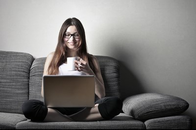 Student working on laptop holding a mug