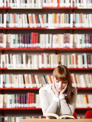 Student reading a book in a library