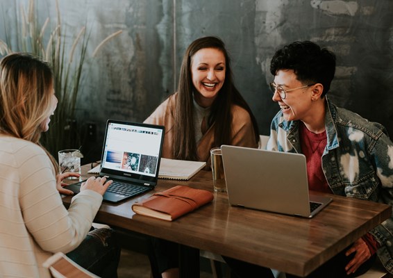 A group of students laughing whilst studying on laptops