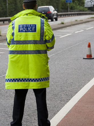 Male met police officer standing in the road for traffic monitoring